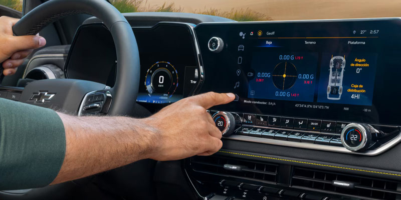 Driver using steering wheel and touchscreen display with vehicle settings and tire pressure information.