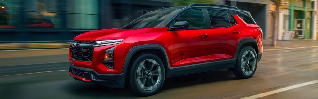 Red 2026 Chevrolet Equinox SUV driving through a city street with motion blur in the background.