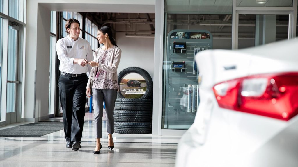 Customer receives vehicle keys from a dealership representative inside the dealership service center.