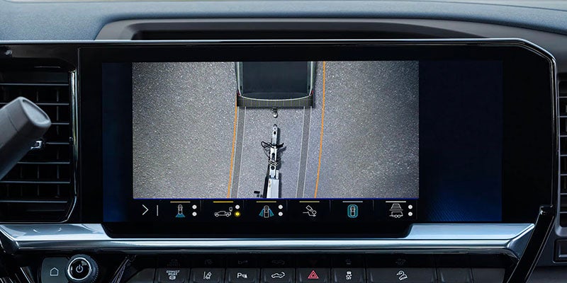A digital display showing a top-down view of a vehicle's rear with guidelines for parking or towing.