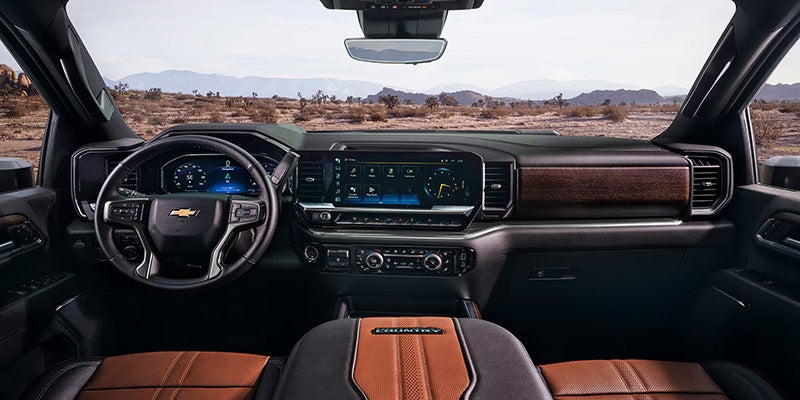 Interior view of a Chevrolet truck, showcasing the dashboard, steering wheel, and center console with modern technology and leather seating.