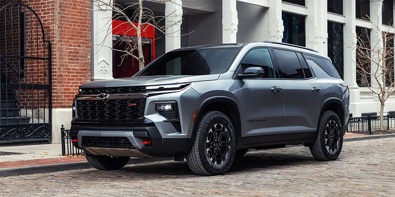 A gray Chevrolet SUV parked on a cobblestone street with buildings in the background.