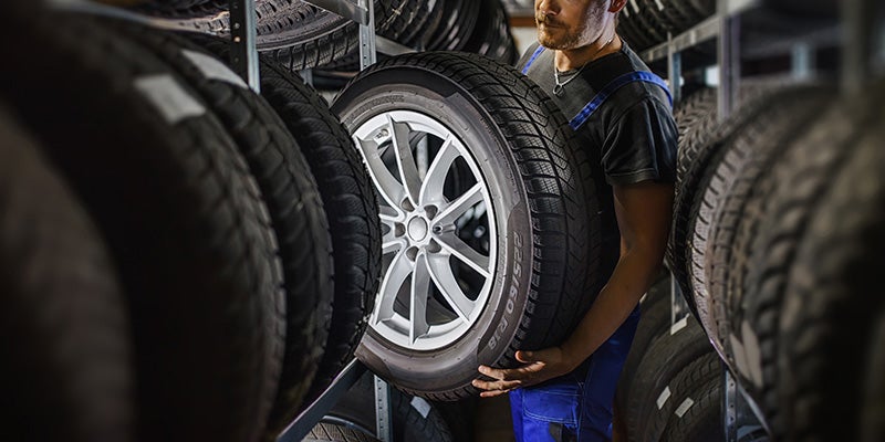 technician from Fitzgerald Chevrolet of Hagerstown in Hagerstown MD carrying a tire
