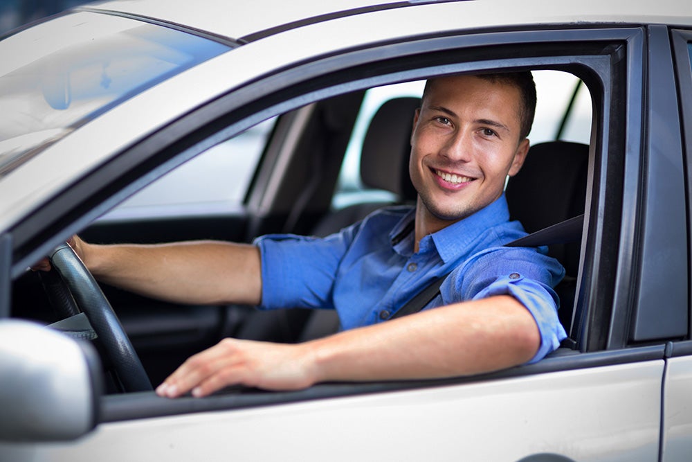 Man smiling out the window of a car